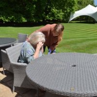 MH In Workplace (6h) lady sitting feeling ill with a standing female looking concerned in a garden