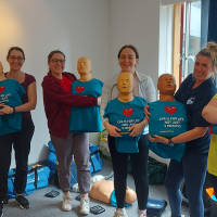 Group of people holding first aid manikins